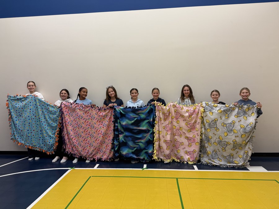 Young volunteers holding their handmade fleece blankets