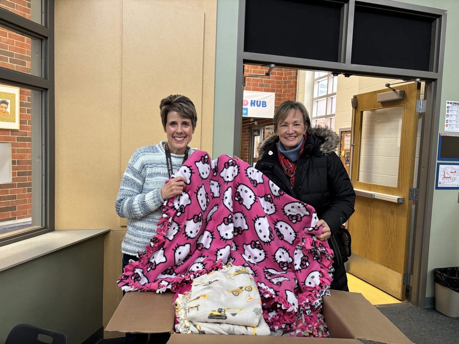 Two volunteers holding a pink handmade fleece blanket