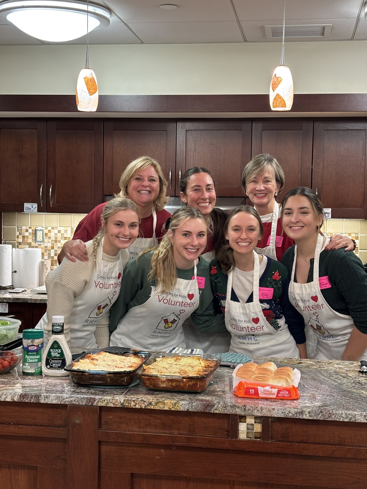 Volunteers together behind a kitchen counter with prepared meals